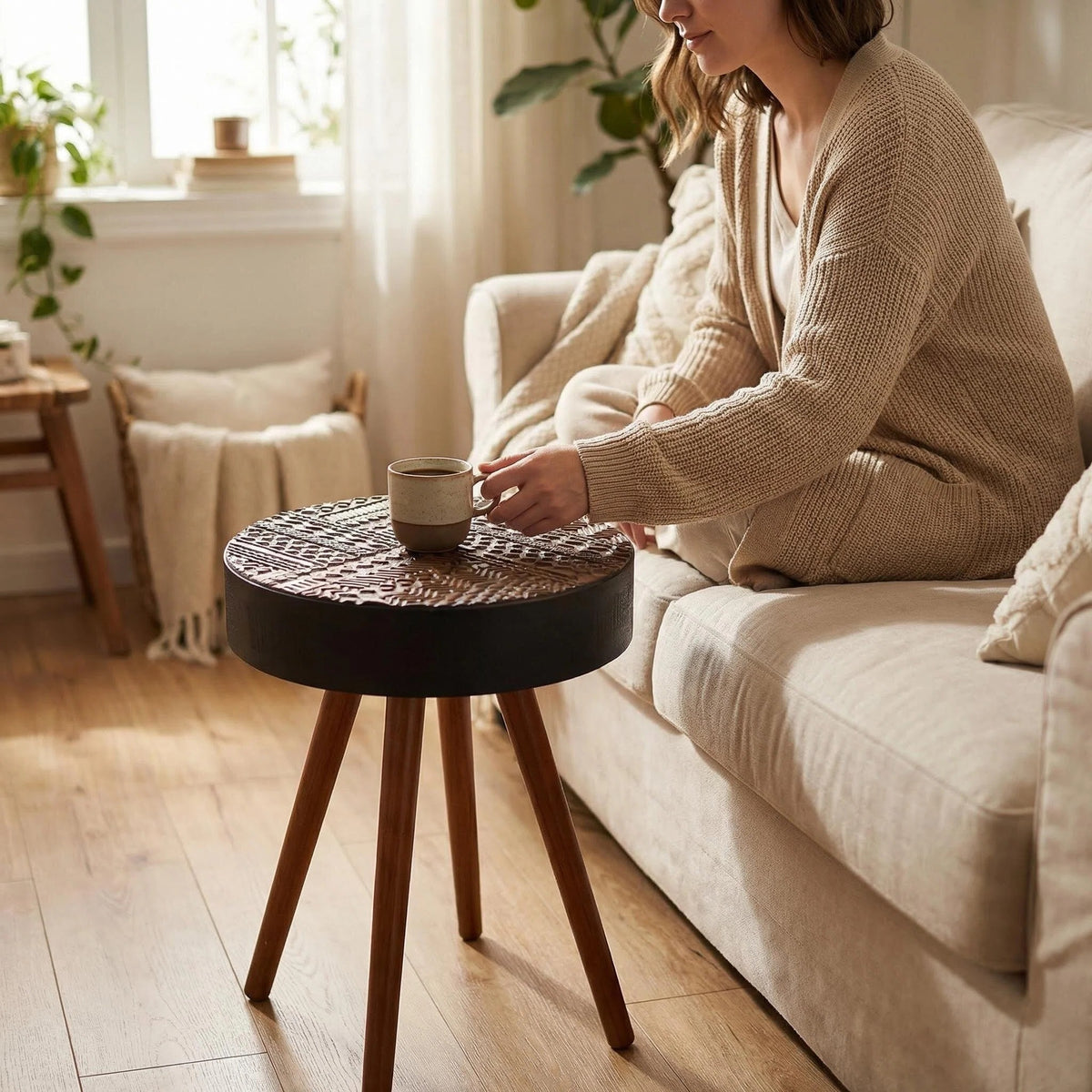 Saxon round side table in black, beside an armchair