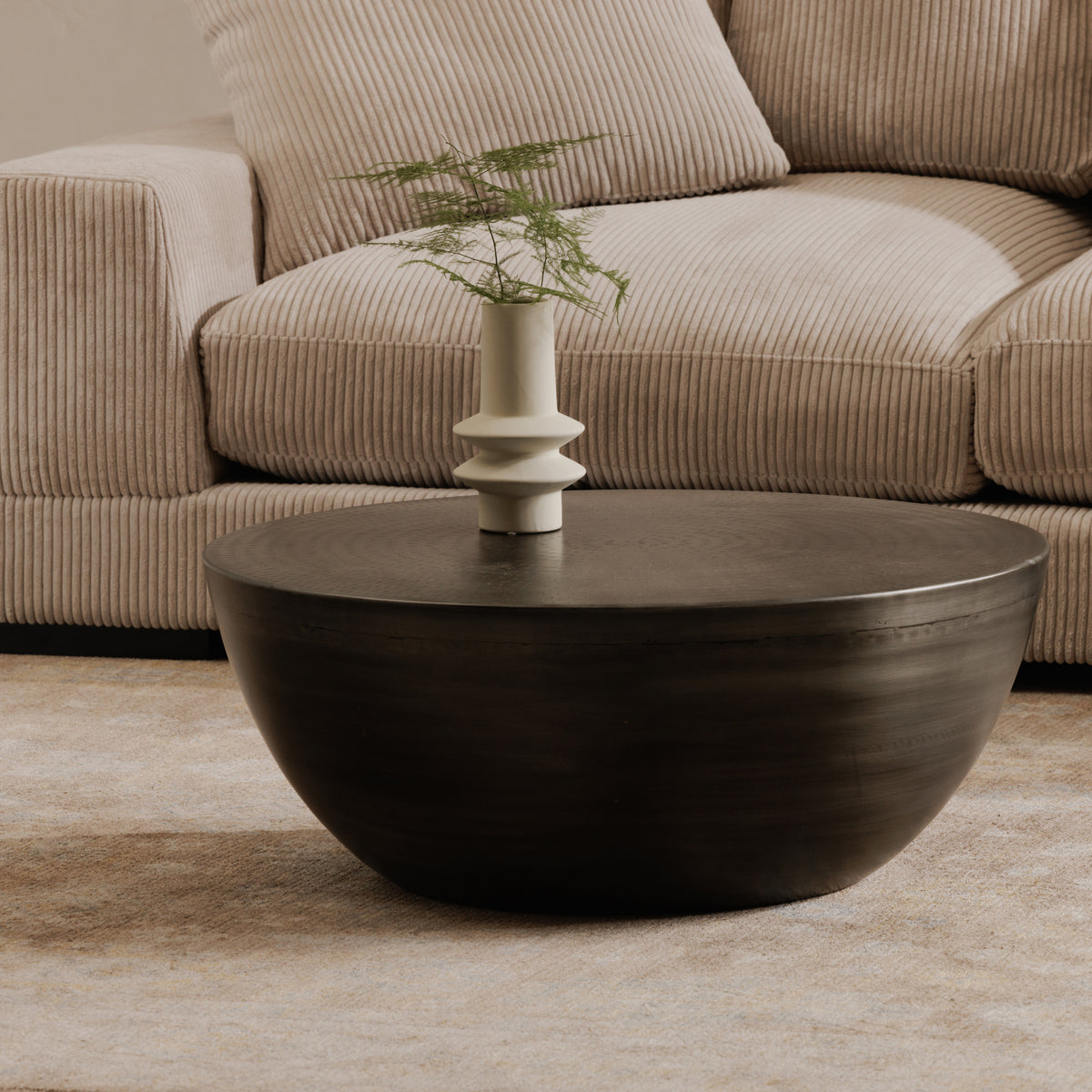 Corniche round metal coffee table in brushed silver, in a living room