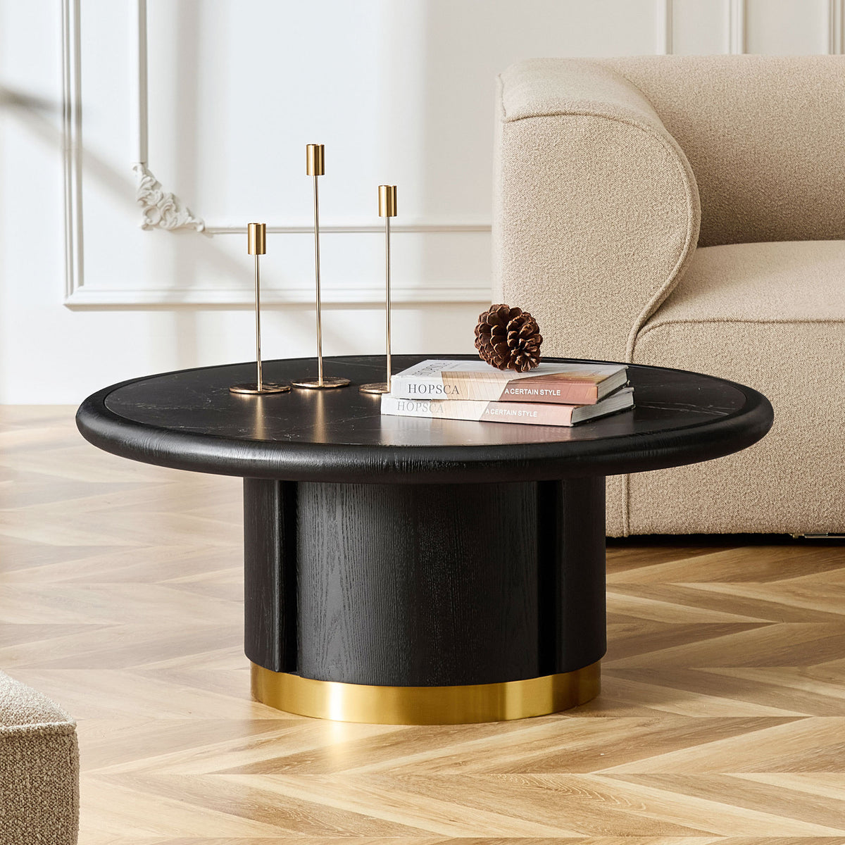 Fontaine round coffee table in black on a cylindrical base, in a living room